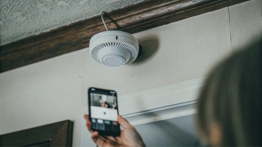 Detector de humo moderno y sistema de alarma conectado a un smartphone.